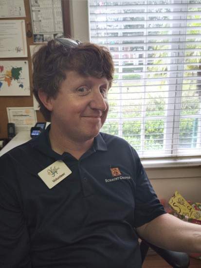 Man sitting with volunteer name tag on his shirt.