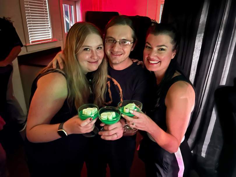 Three women in the secret saloon holding drinks 